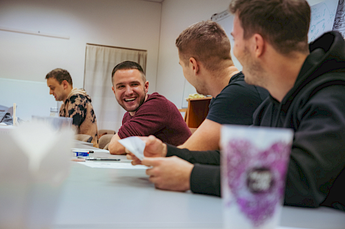 Tím sediaci za stolom v zasadačke, uprostred CEO, usmievajúci sa