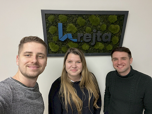Projektový manažér, projektová manažérka a CEO pod logom Krejta zaveseným na stene